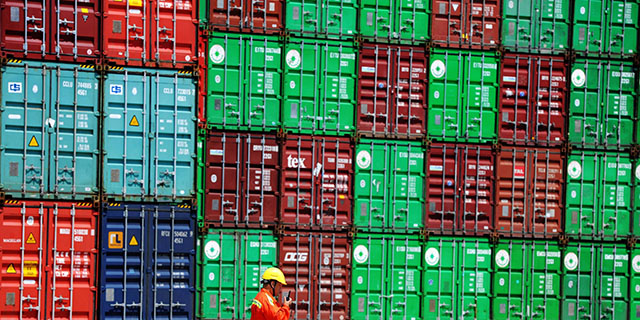 A worker walks by stacked containers at the port in Qingdao, China. (VCG/VCG via Getty Images)