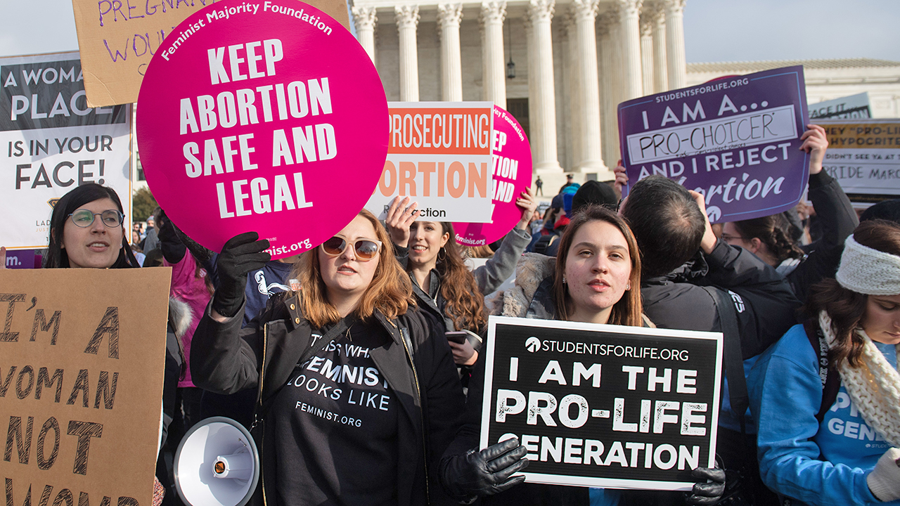 Pro-choice activists hold signs alongside anti-abortion activists participating in the "March for Life" in Washington, DC, in January 2019. (SAUL LOEB/AFP via Getty Images)