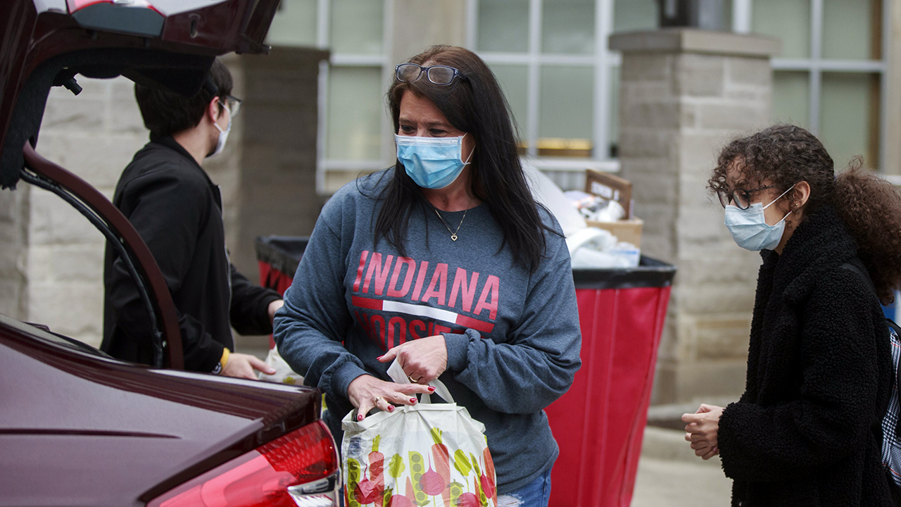 A mother in a mask helps move her daughter back home from a dorm at Indiana University on March 20. Students were told to vacate student housing due to the coronavirus emergency. (Jeremy Hogan/SOPA Images/LightRocket via Getty Images)