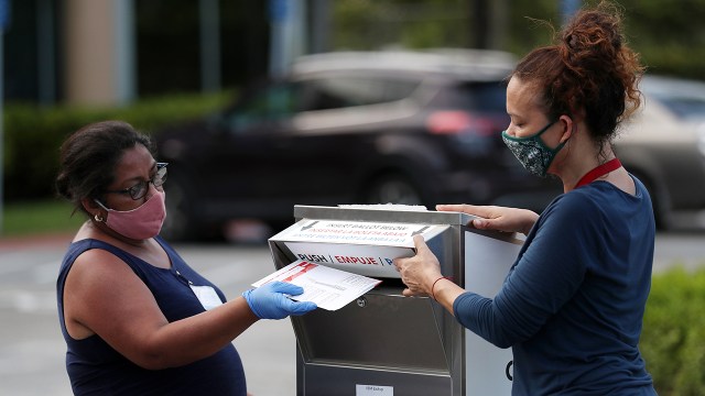 Poll workers deposit mail-in ballots on primary day on August 18, 2020, in Doral, Florida. (Joe Raedle/Getty Images)