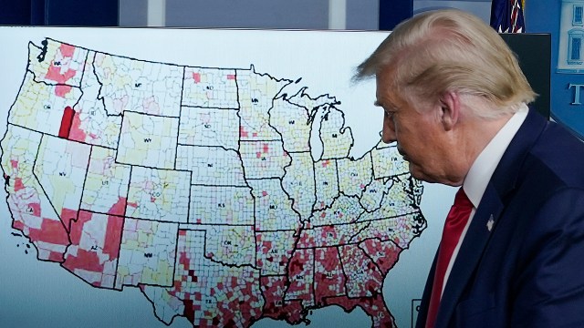President Donald Trump in July walked by a map of U.S. coronavirus cases per 100,000 people. (Drew Angerer/Getty Images)