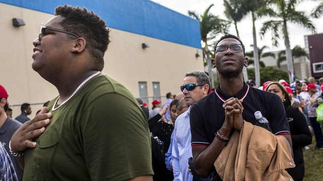 Two men sing along with Christian music played over loudspeakers while waiting in line for an "Evangelicals for Trump" rally in Miami in January 2020. (Scott McIntyre/The Washington Post via Getty Images)