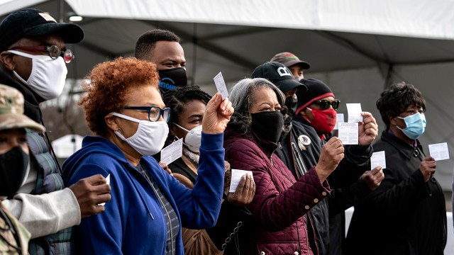 Coronavirus vaccine recipients show off their vaccination record cards in the parking lot of Six Flags in Bowie, Maryland, on Feb. 6, 2021. The state is using the lot as a mass vaccination site. (Sarah Silbiger/Getty Images)