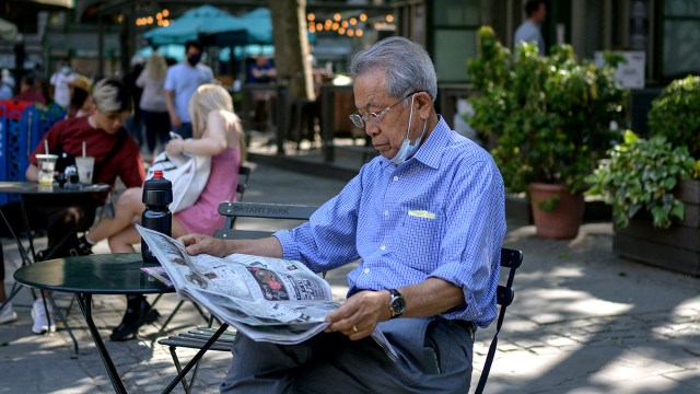 A man reads a newspaper in Bryant Park in New York City on May 19, 2021, as COVID-19 restrictions are lifted. (Ed Jones/AFP via Getty Images)