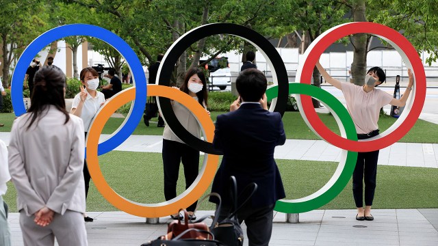 People wearing face masks take a photo in front of the Olympic Rings installation at the Olympic Square in Shinjuku, Japan.