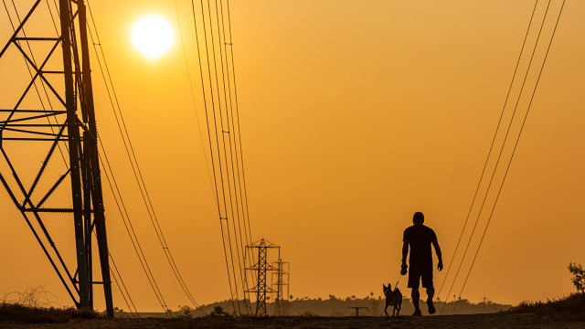 Smoke-filled skies cast an orange hue at sunset as a man and his dog walk in Laguna Hills, California, on Sept. 16, 2020.