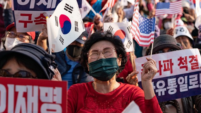 A pro-government protester waves American and South Korean flags during a day of two opposing political rallies in downtown Seoul, South Korea, on Oct. 22, 2022.