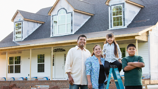 Hispanic family smiling outside house under construction