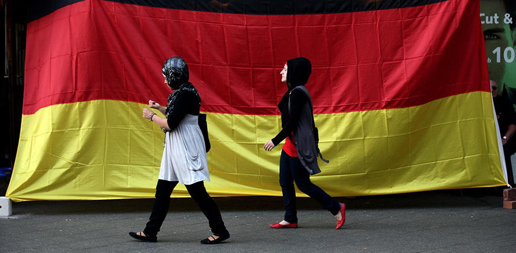 BERLIN - JULY 07: Two young Muslim women walk by a pub draped in a German flag in the Arab and Turkish-heavy neighborhood of Neukoellsn during the FIFA 2010 World Cup match between Germany and Spain on July 7, 2010 in Berlin, Germany. Many immigrants in Germany identify strongly with the German national team, in part because many of the team's members have African, Arab, Turkish or East European roots. (Photo by Sean Gallup/Getty Images)
