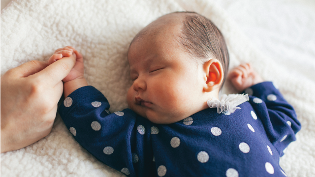 A baby girl holds her mother’s hand. (Tuan Tran/Getty Images)